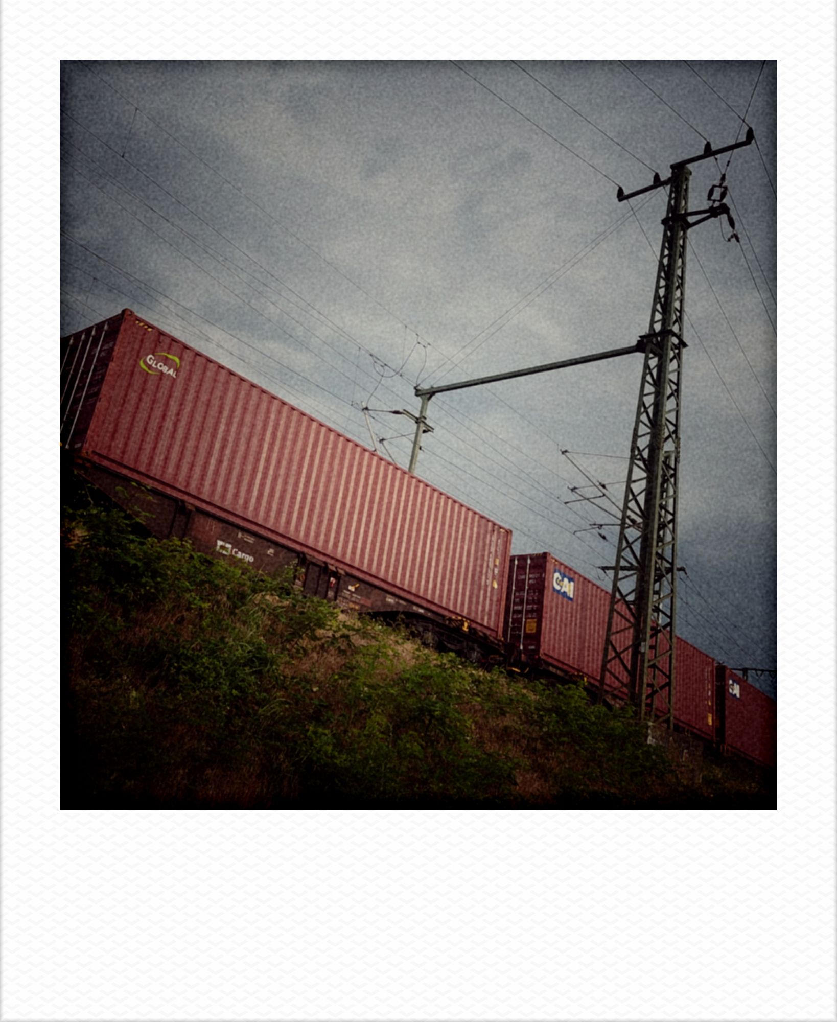Freight train on a railroad track, seen from slightly below in early morning light.