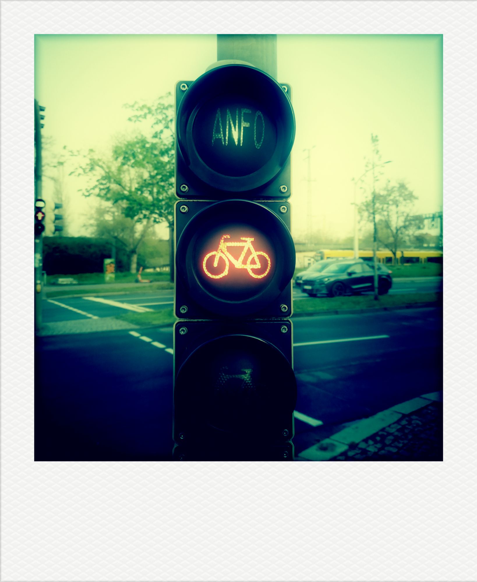 Traffic light for cyclists on red. A tram and a street scene in the back.