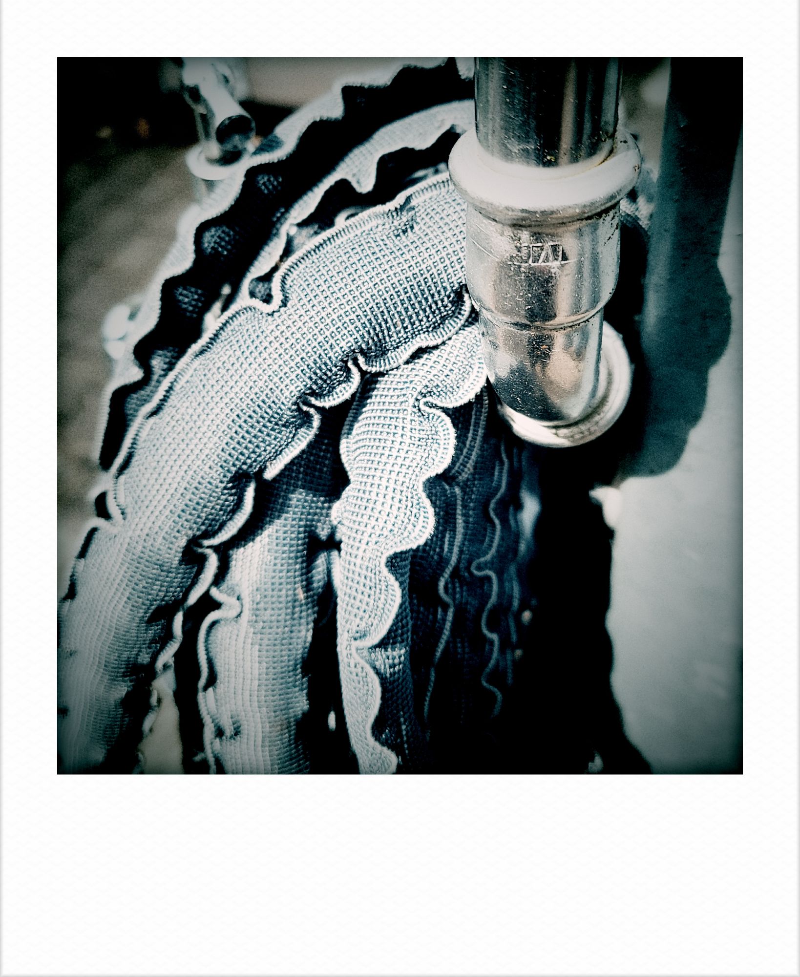 An old water hose, rolled up around a pipe.