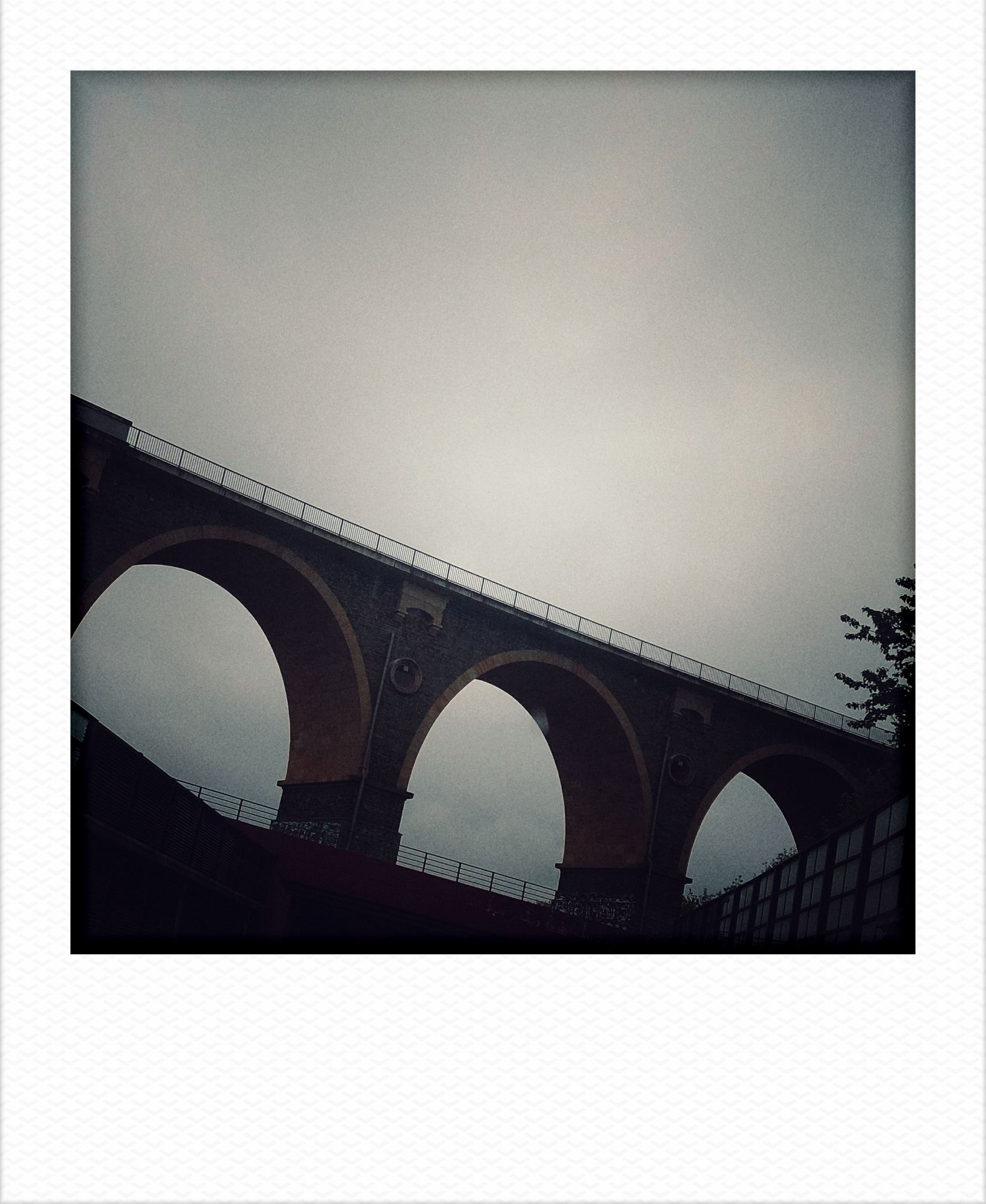 A train bridge in front of grey sky.