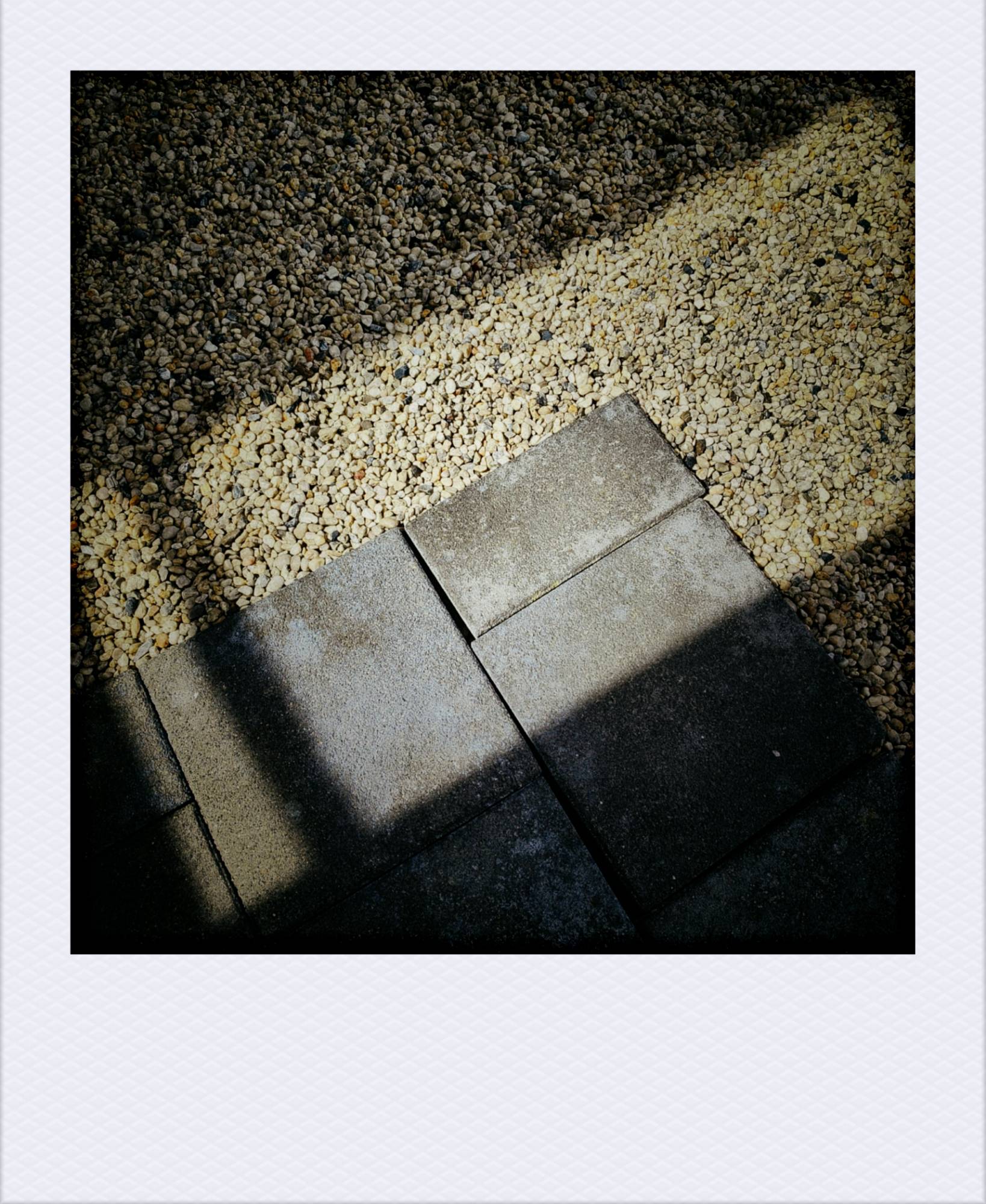Stones on an office terrace, and a rectangle of strong sunlight on it.