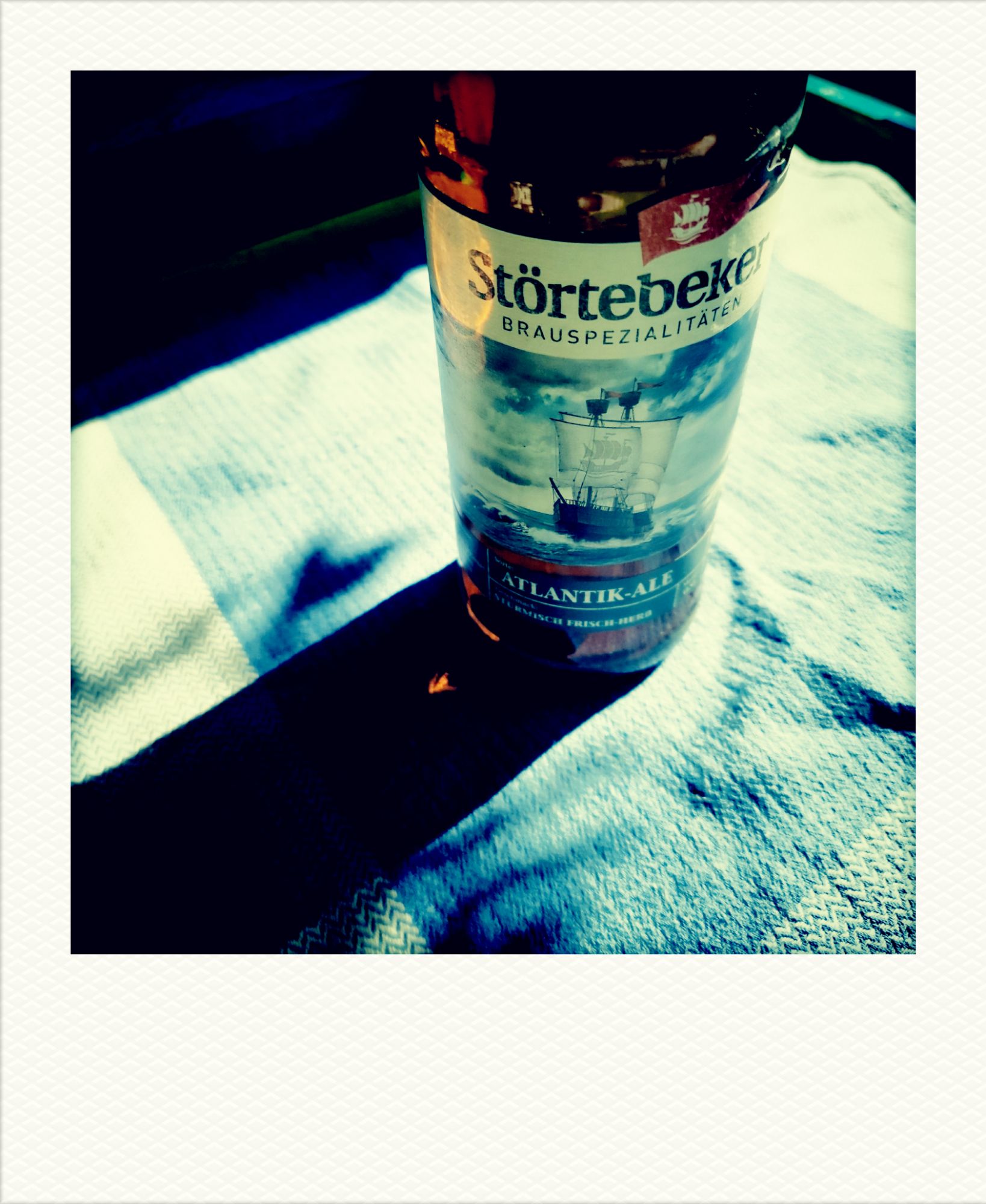 A bottle of Störtebeker Atlantic Ale on a squared blue and white tablecloth.