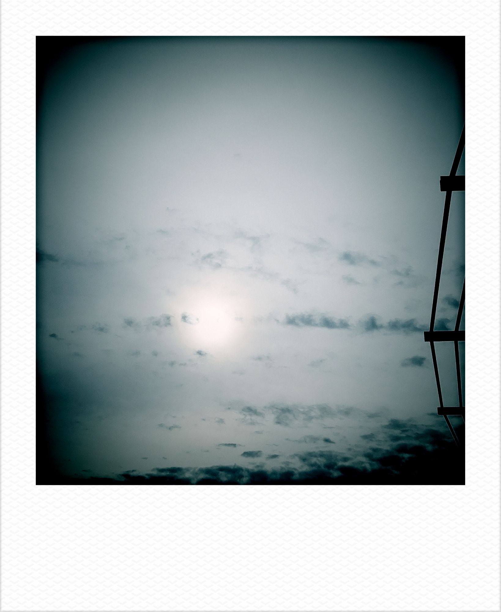 Sun in cloudy sky. Part of an office roof on the right.