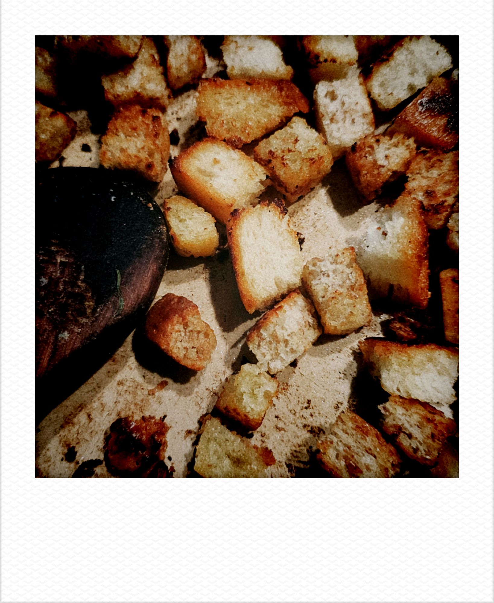 Croutons and a wooden spoon in a frying pan.