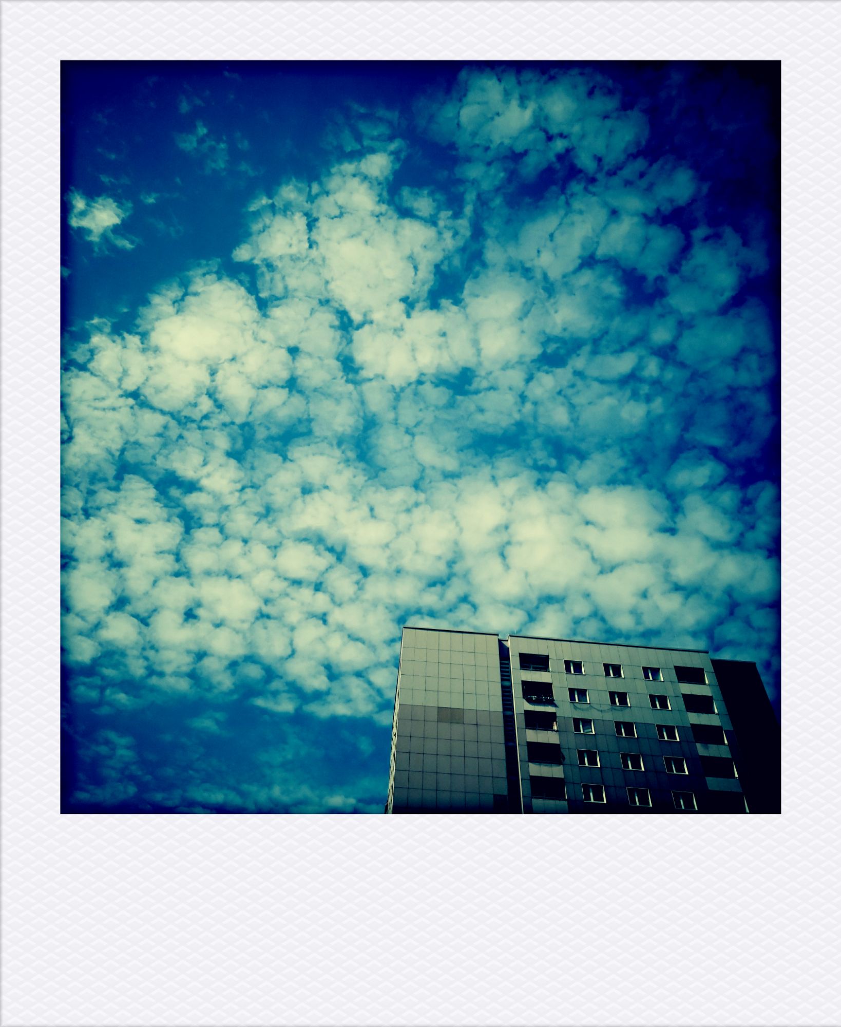 White clouds behind a high-rise.